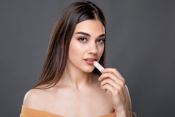 Young beautiful woman testing and applying lipstick or lip balm, skin and lips care, Chap protection - obrazy, fototapety, plakaty