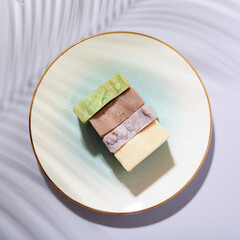 Handmade brown soap bars  with organic ingredients on a plate and purple background. Homemade beauty products with natural essential oils from plants and flowers. Body care, aromatherapy.