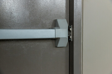 Emergency fire exit door. Closed up latch and rusty door handle of emergency exit. Push bar and...