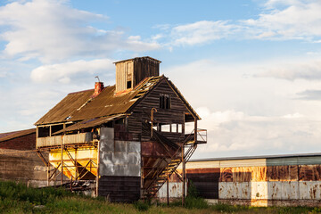 Old abandoned agricultural building with rusty iron walls. Soviet and Russian rural