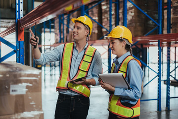 Warehouse Workers Checking Stock with digital Tablet in Logistic center. Caucasian worker wearing hard hat and safety vests to talking about shipment in storehouse, Working in Distribution Center.