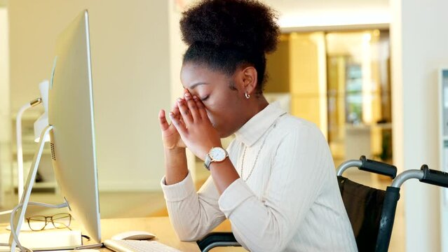 Stressed disabled bussineswoman having a mental breakdown and suffering from headache at her computer in an inclusive workplace. Depressed woman in wheelchair struggling to cope with the workload