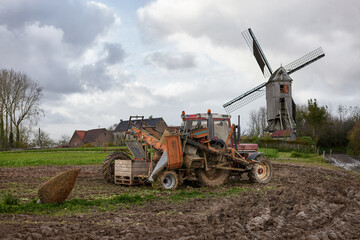 Fototapeta premium Old tractor on field with windmill in background