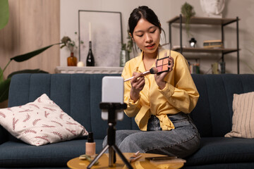 Fototapeta premium Japanese Blogger Woman Filming Video On Phone Making Makeup Indoor