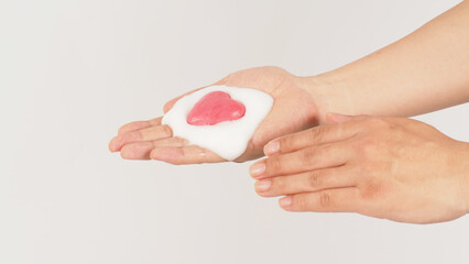 Hands washing with foaming and pink soap on white background. Studio shot