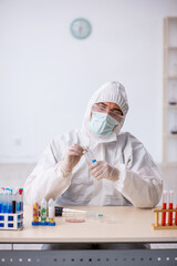 Young male chemist in drugs synthesis concept