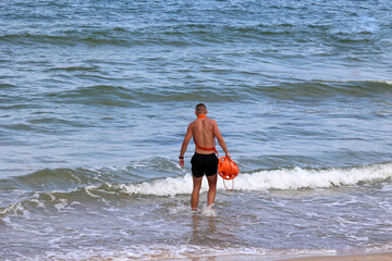 Ratownik na plaży podczas patrolowania brzegu wody.  - obrazy, fototapety, plakaty