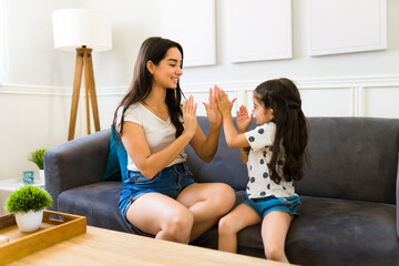 Happy mother and little girl enjoying a singing game at home