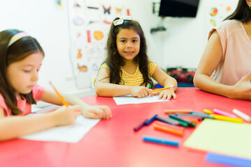 Latin kindergarten student holding a pencil and writing