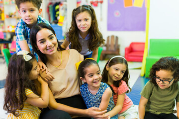Lovely preschool teacher giving love to her students - Powered by Adobe