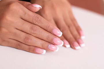 Obraz na płótnie Canvas Close up view of beautiful female hands with luxury french manicure nails on white background 