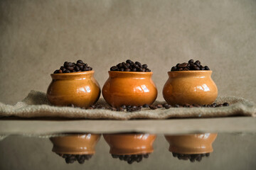 Clay pots filled with freshly roasted coffee beans stand in a row, close-up. Assortment of coffee varieties for connoisseurs of refreshing drink.