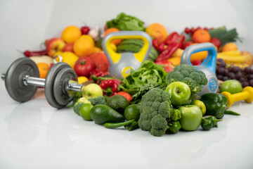 Fitness concept. Healthy nutrition: fruits and vegetables. Equipment for fitness exercises: weighing machine and dumbells. White background.