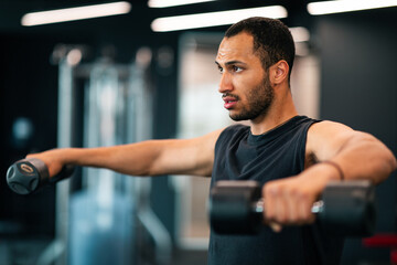 Portrait Of Motivated African American Male Athete Training With Dumbbells At Gym
