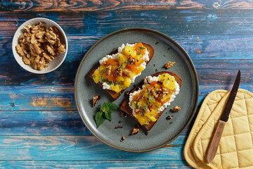 Fruity topped bread with caramelized mango pieces on cottage cheese. Healthy toast (tartine). 