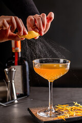 Professional female bartender flavoring a luxury cocktail with impressively spray from citrus peel. Cocktail zest shoot - obrazy, fototapety, plakaty