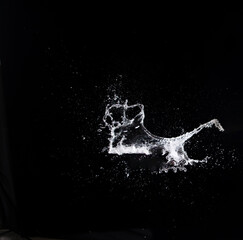 Water splash in air drop over black background, studio lighting high speed