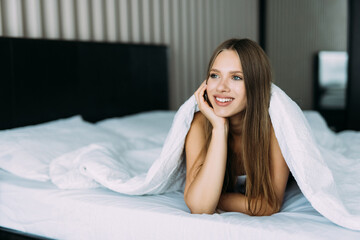 Beautiful woman in bed under the sheets at home