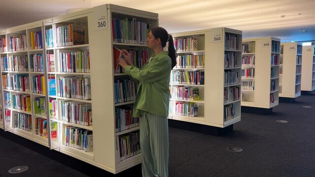 Girl Takes Book From Stand In Library