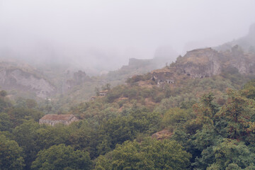 Fog view on the Khndzoresk ancient cave city in the mountain rocks. Armenia landscape attraction. Abandoned ruins in the mist. Atmospheric stock photography.