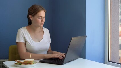 Charming girl working on laptop during breakfast at cafe, woman sitting at coffee shop