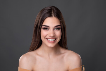 Obraz premium Beautiful young woman with clean perfect skin. Portrait of beauty model with natural nude make up and touching her face. Spa, skincare and wellness. Close up, copyspace. Stock photo