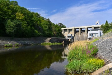 Fototapeta na wymiar A dam on the Brno Reservoir by the Svratka River with a small power plant. Kninicky hydropower plant. The power plant uses one Kaplan turbine.