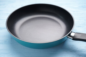 Frying pan and kitchen towel on a blue wooden background, closeup.