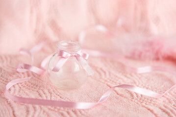 Fototapeta na wymiar small glass bottle and ribbons on a gentle pink background. Card.