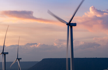 Wind energy. Wind power. Sustainable, renewable energy. Wind turbines generate electricity. Windmill farm on a mountain with sunset sky. Green technology. Renewable resource. Sustainable development.