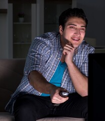 Young man watching tv late at night