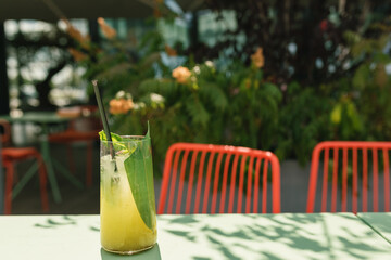Tropical lemonade in tall glass on sunny terrace. Copy space.