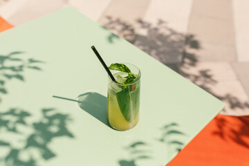 Green lemonade in tall glass on pastel green background with leaf shadows. Minimalistic still life. Copy space. - obrazy, fototapety, plakaty