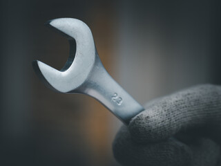 Working man wear the cloth gloves and hold the wrench preparing to tighten the nut. Worker or labor day concept.