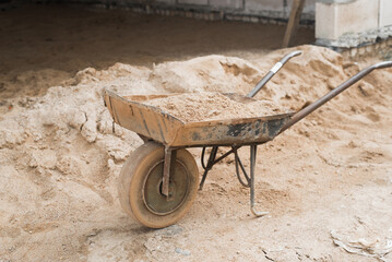 Construction cart with sand outdoors. Wheelbarrow for transportation of cargo and cleaning of...