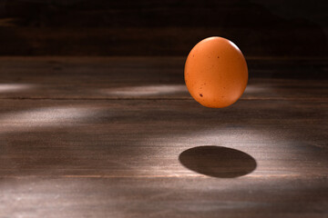 one raw egg flying over wooden table
