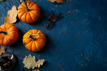 Small pumpkins and leaves on dark blue surface halloween concept copy space