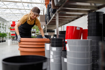 Pretty woman in uniform working in a shop with flower pots