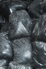 Background pile of dusty dirty black plastic bags with garbage