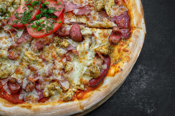 Pizza with meat sausage and chicken, cheese and tomatoes on a gray concrete background, with selective focus