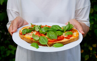 delicious large Italian bruschetta with mozzarella, garlic, olive oil and basil leaves on a plate