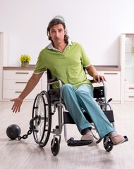 Young male invalid in wheel-chair suffering at home