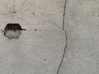 Perfect background shot for designers of a beautiful unique beige grey white wall with a lock decoration at the left and a deep crack in the wall at the right