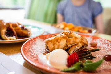 Macro view of strudel with ice-cream and berries on table in outdoor area of restaurant in summer
