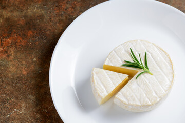 Camembert Cheese with rosemary on white dish.
