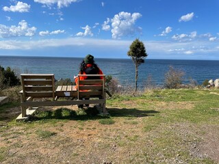 Fototapeta premium lonely woman sitting on a bench by the beach on a beautiful weather