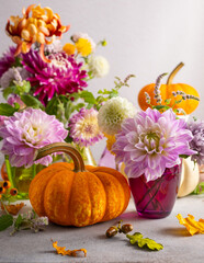Autumn still life with bouquet of flowers and white and orange pumpkins on table. Autumn decoration...