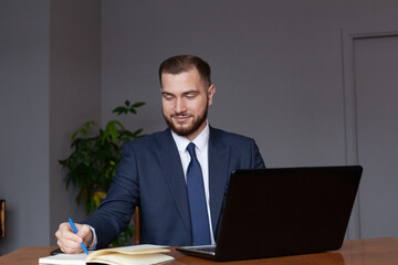 Smiling businessman with laptop computer, notebook and documents at office