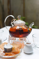  Earl Grey tea in glass teapot with cups and crystalized fruits on wooden background