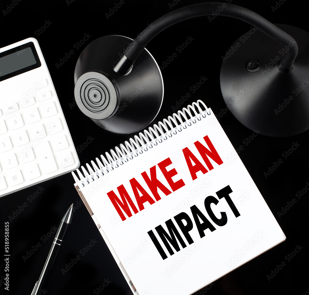 Poster opened paper notebook with text make an impact with a pen, calculator and table lamp on black backgr